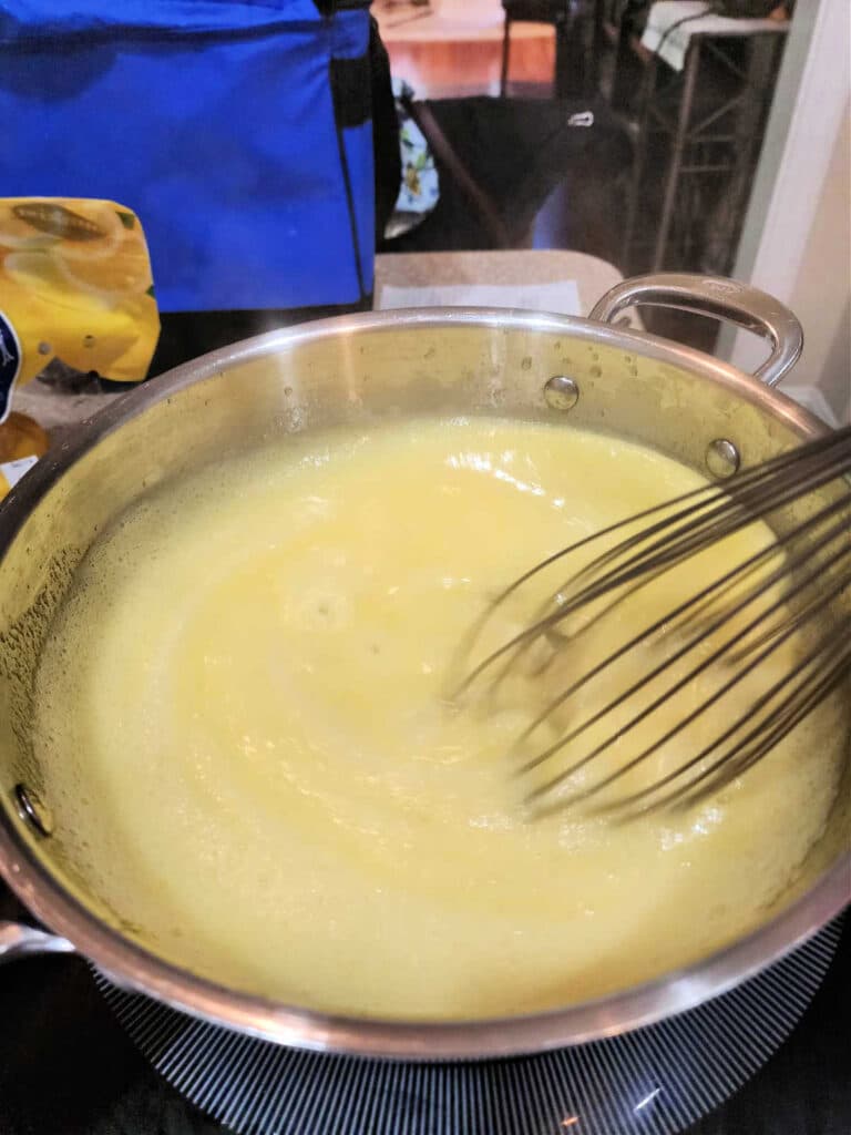 Whisking pale yellow, thick pudding in a pot.