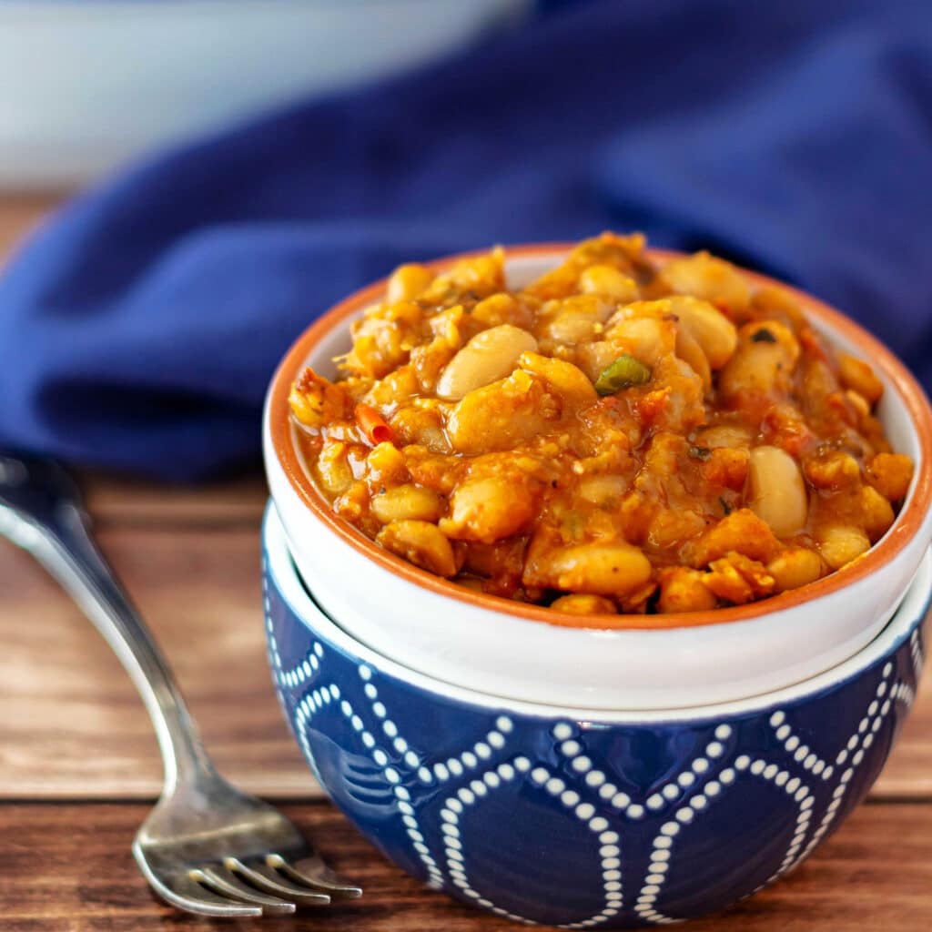 A white bowl stacked in a dark blue bowl with baked beans in it.