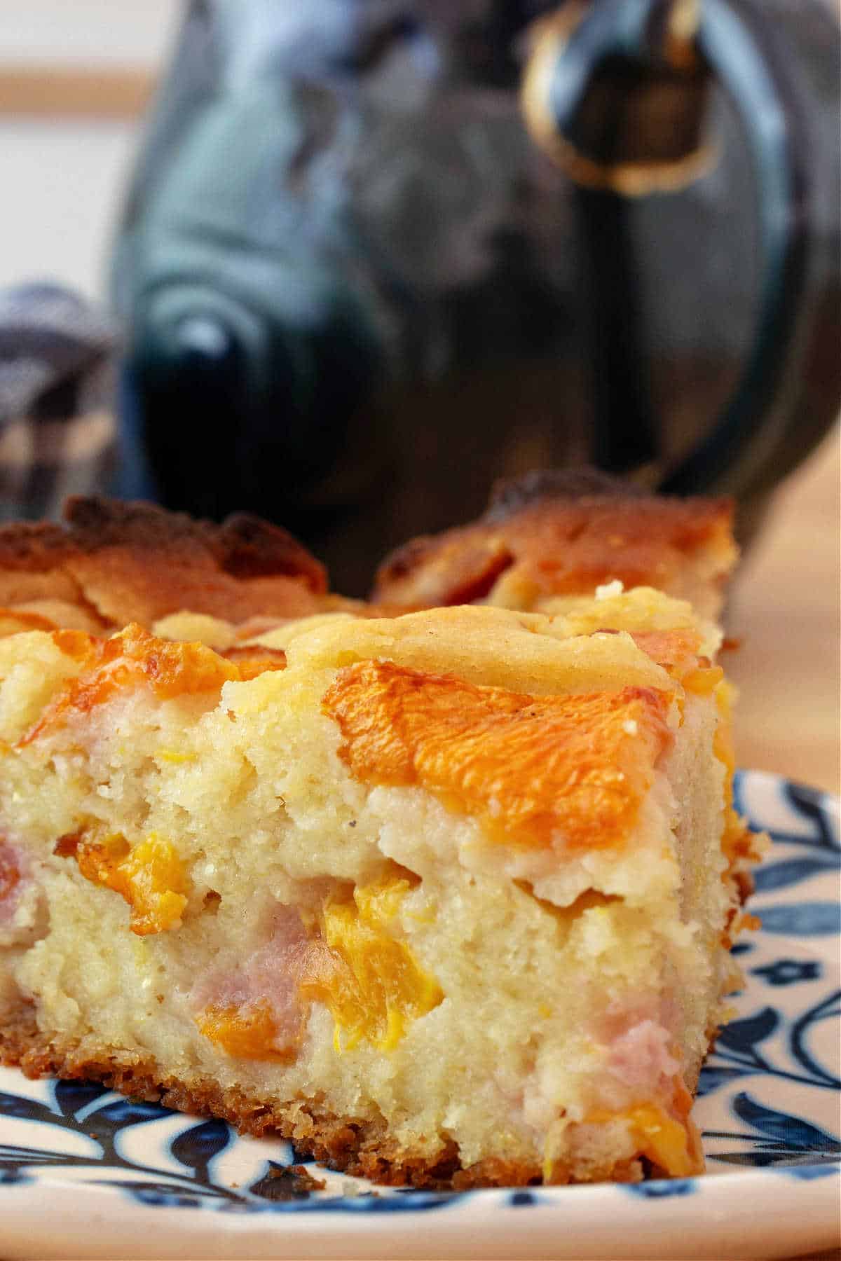 A close up of the side of a cake showing lots of diced peaches in it as well as sliced peaches on top.