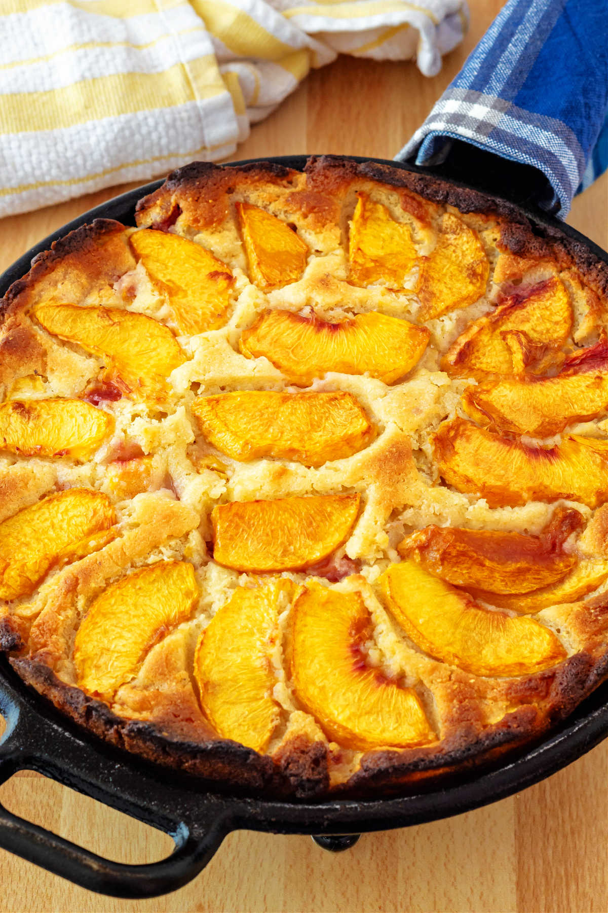 A close-up of a peach breakfast cake topped with sliced peaches in a cast iron skillet.