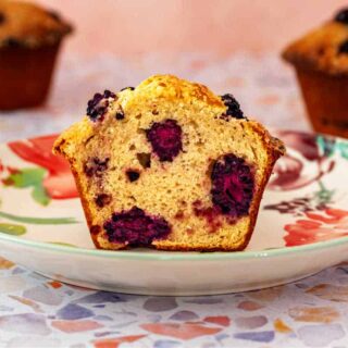 A cross-section of a jumbo muffin revealing all the purple blackberries in it.