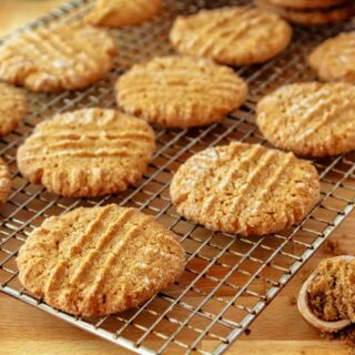A wire rack with peanut butter cookies cooling on it.