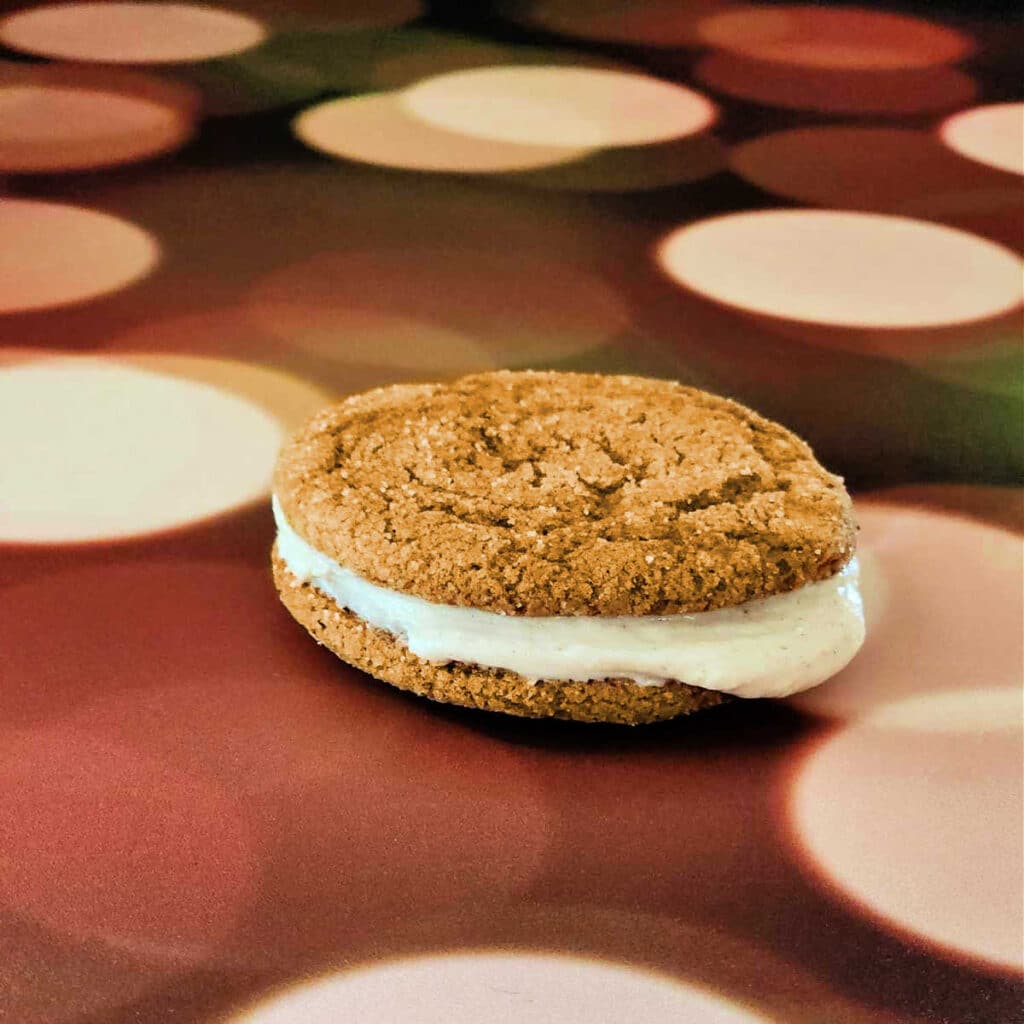 Two ginger cookies sandwiched together with pumpkin spice cream cheese frosting.