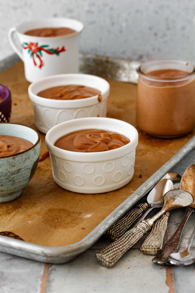 A parchment-lined tray with dishes and ramekins of chocolate mousse on it.