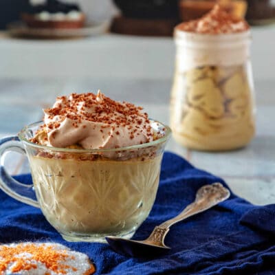A cut glass teacup of coffee mousse with another small, glass jar of mousse in the background.