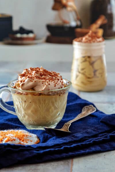 A cut glass teacup of coffee mousse with another small, glass jar of mousse in the background.