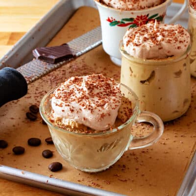 Several glass containers of coffee mousse on a sheet tray.