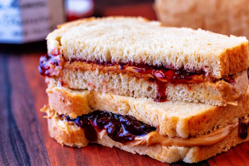 Closeup of a peanut butter and jelly sandwich made on homemade oatmeal bread The sandwich is cut in half with the halves stacked on top of each other.