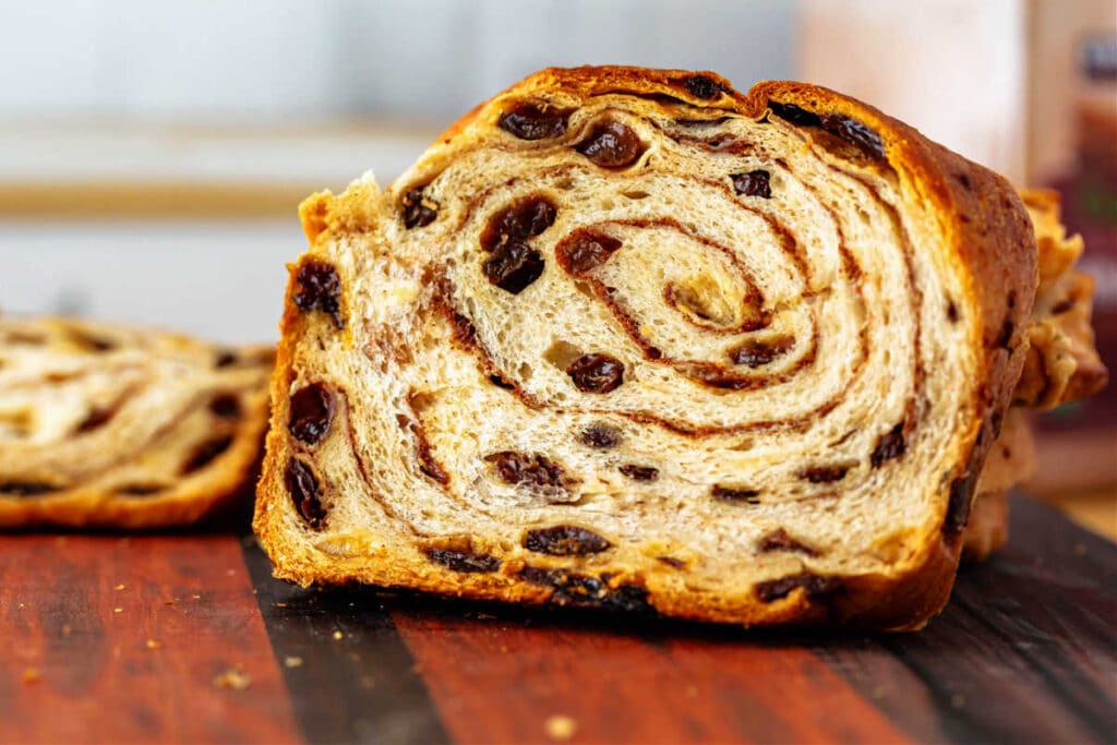 A close-up of a slice of raisin bread showing a gorgeous swirl of cinnamon sugar spiraling around several times.