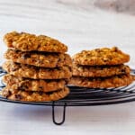 Two stacks of oatmeal cookies on a round black wire cooling rack.