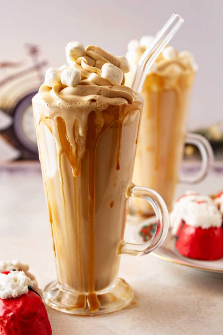 Two tapered, handled clear glasses full of hot butterscotch and topped with lots of whipped cream and mini marshmallows.