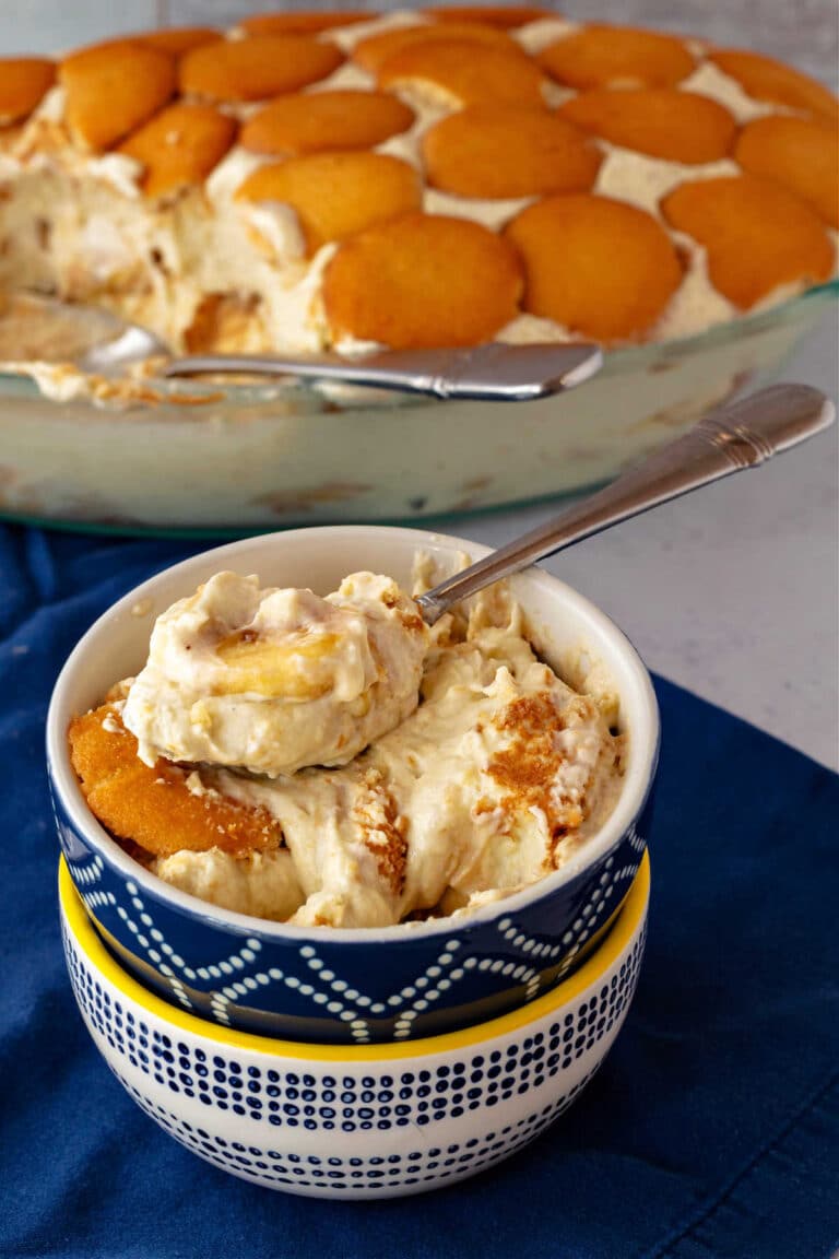 A large bite of banana pudding on a spoon on top of a dish of banana pudding.