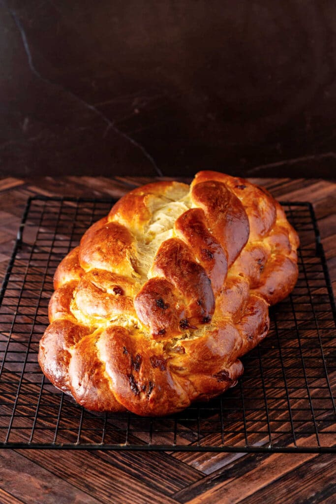 A baked loaf of houska on a cooling rack. The sweet bread is deeply golden brown thanks to the egg wash.