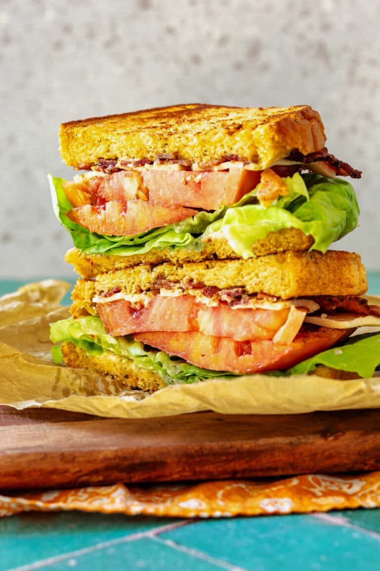A BLT cut in half and stacked to show layers of bacon, lettuce, and tomato.