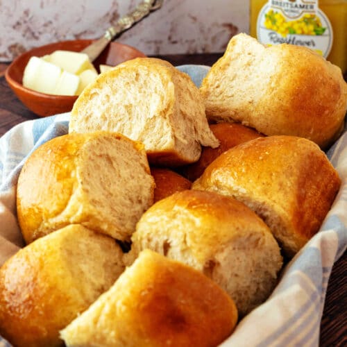 A basket of plush honey wheat steakhouse-style dinner rolls with shiny tops.