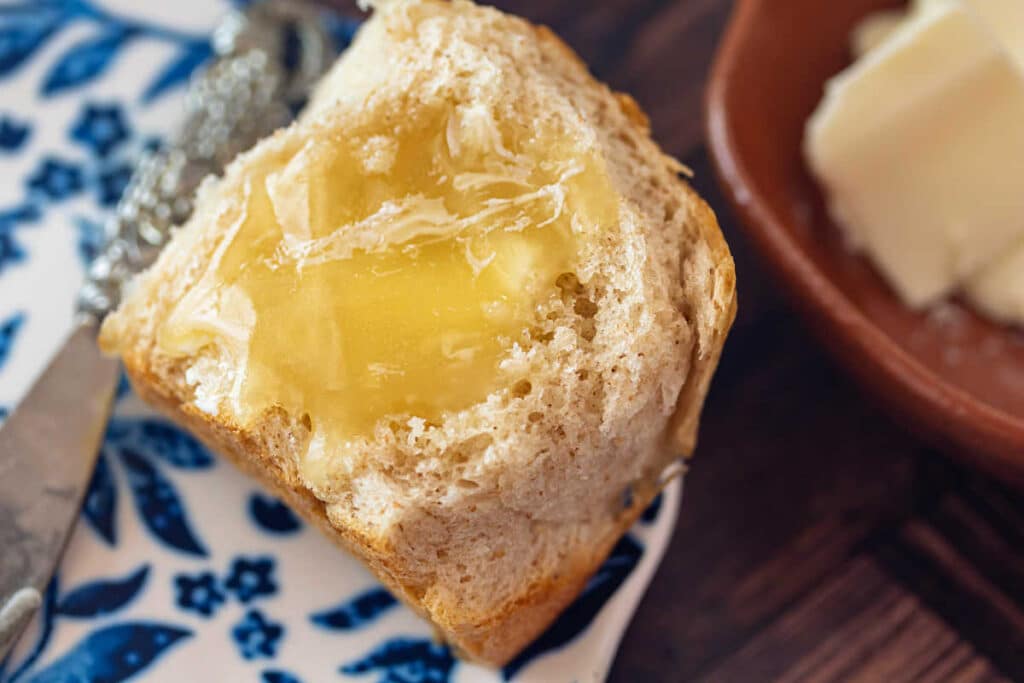 A closeup of a honey wheat roll slathered with butter and honey.
