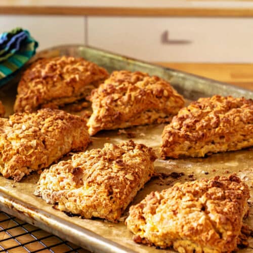 Baked scones on a baking sheet cooling on a rack.