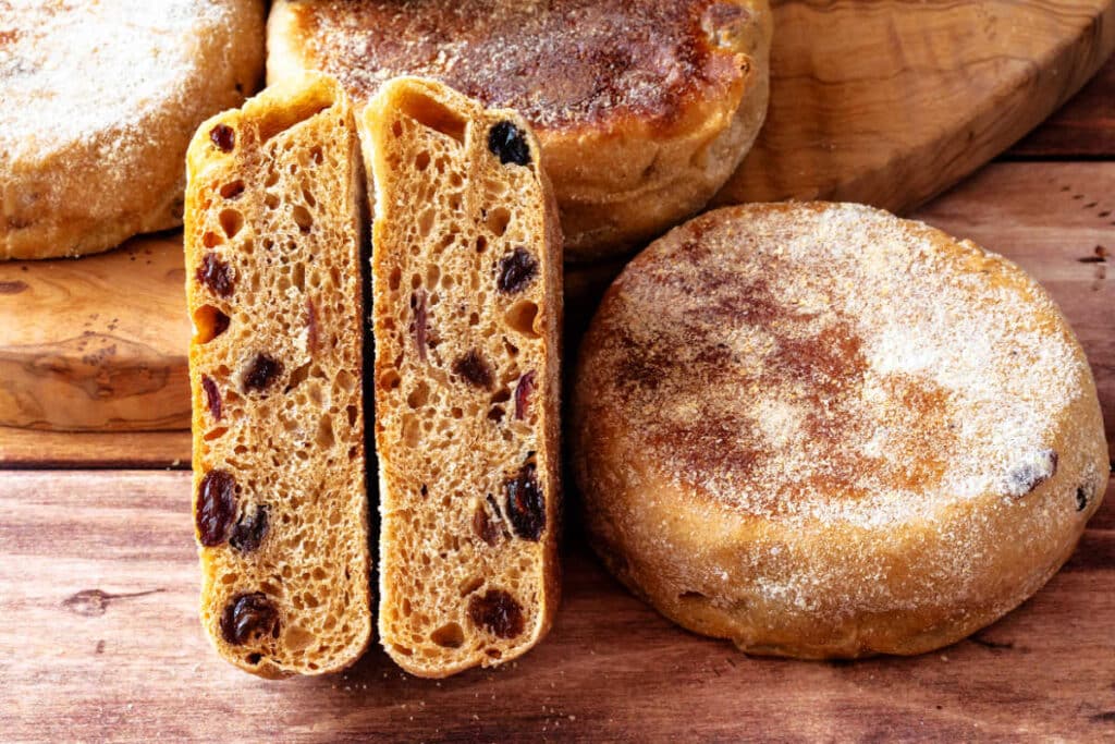 A cinnamon raisin English muffin sliced in half showing the interior crumb and generous distribution of raisins.