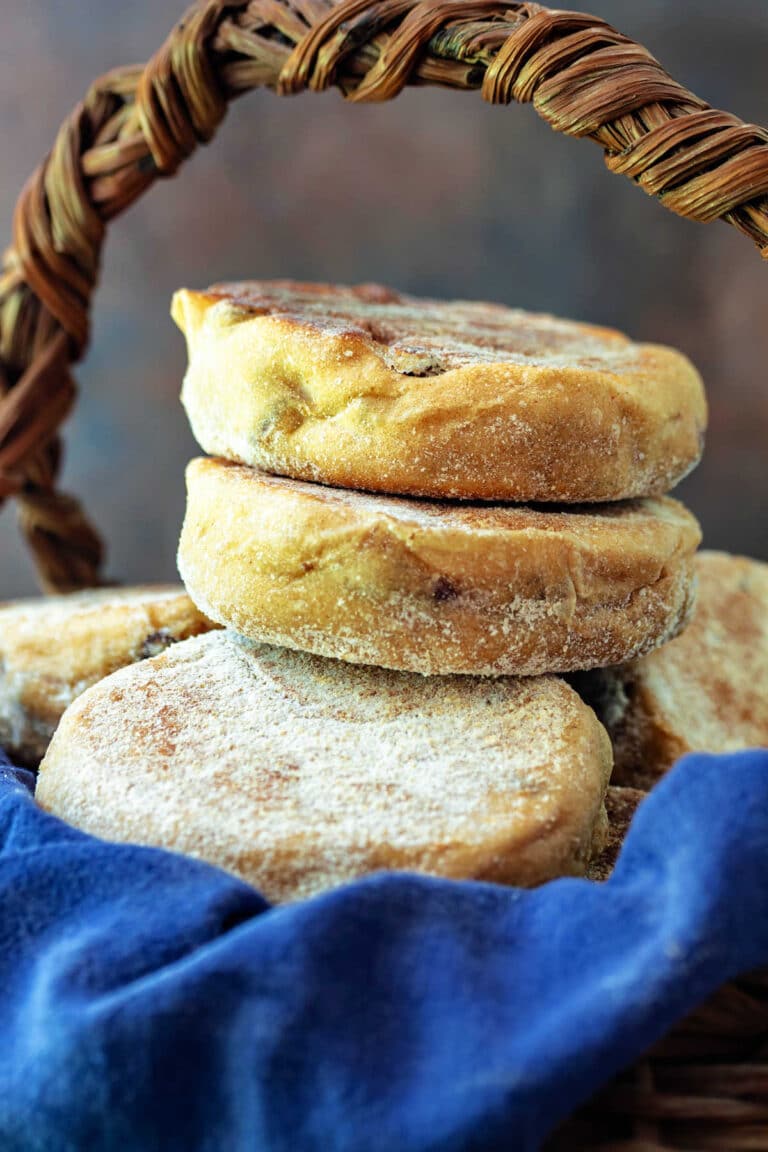 A close-up of a blue cloth-lined basket of homemade English muffins.