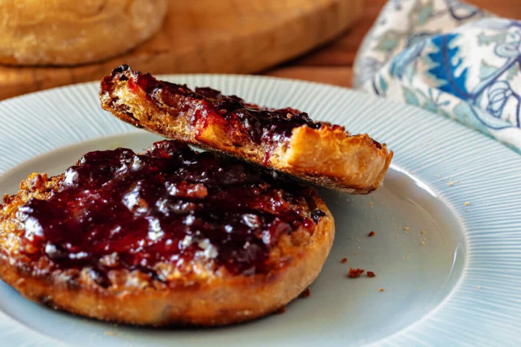 Toasted cinnamon raisin English muffin with melted butter and blueberry jam.
