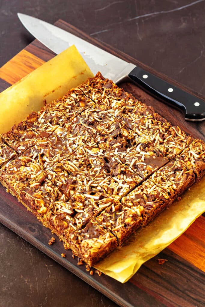 Peanut butter butterscotch magic bars cut into squares, topped with toasted coconut and butterscotch sauce.