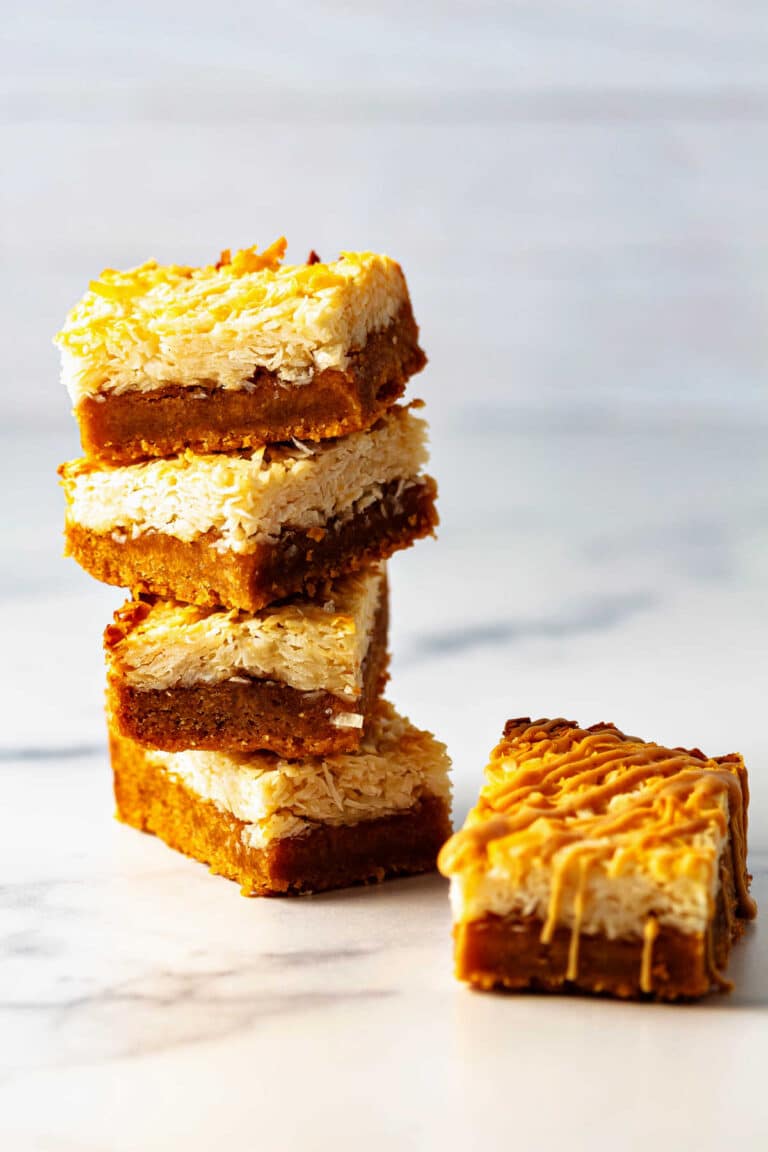 A stack of layered bars with a fudgy peanut butter layer topped by a layer of coconut macaroon.