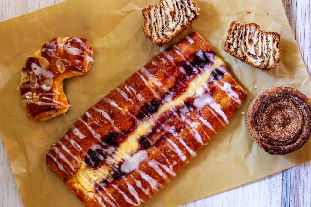 An overhead shot of various Danish pastries arranged on a piece of unbleached parchment paper.