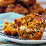 A cross section of a pumpkin muffin studded with chopped cranberries and pecans with a Greek yogurt ribbon running through the center.